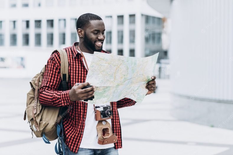 handsome-happy-afro-american-tourist-with-old-camera-map-modern-city_2139-19